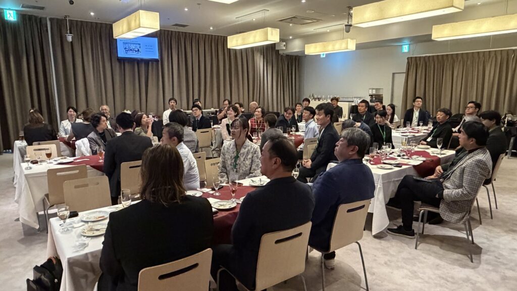 GSJ 6周年記念パーティーの会場全景。円卓に着席した参加者がステージの方を向いて話を聞いている
