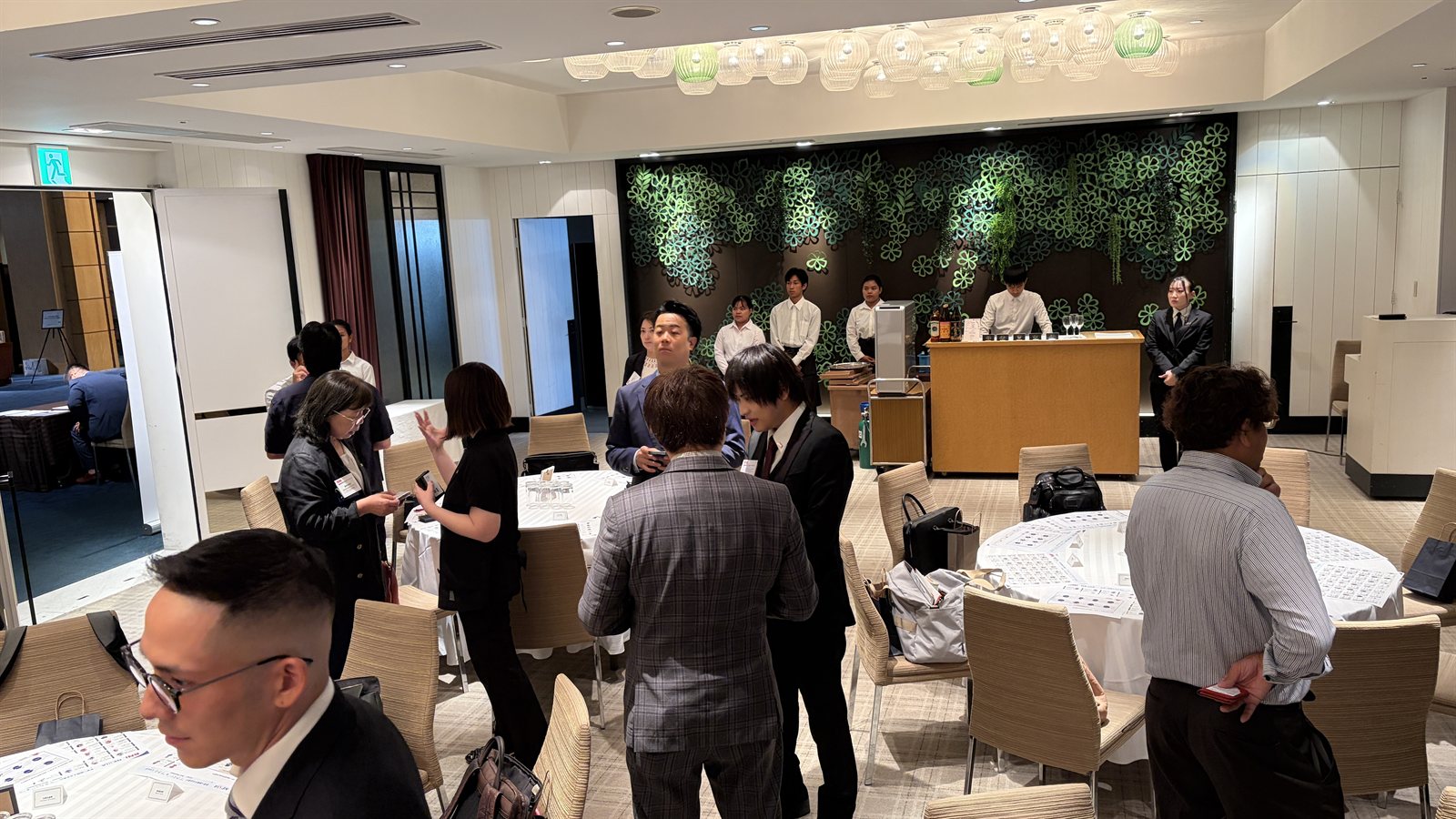 設立記念パーティー会場での交流の様子。参加者が立ち話で名刺交換や情報交換を行っている